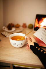 Open book. Lit candle. Woman holds a cup of tea in her hand and cozy atmosphere. Still life. Working atmosphere.