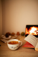 Open book. Lit candle. Cup of tea and cozy atmosphere. Still life. Working atmosphere.