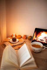 Open book. Lit candle. Cup of tea and cozy atmosphere. Still life. Working atmosphere.