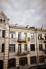 Obraz premium Window view on Andriyivsky Uzviz in Kyiv, Ukraine. Ukrainian flag hangs on a balcony. Sunset light.