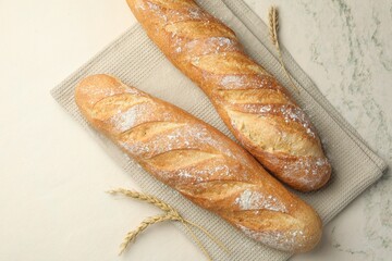 Fresh baguettes and spikes on beige textured table, flat lay
