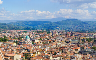 A bird's-eye view of Florence, italy reveals a breathtaking panorama of the city's iconic red-tiled rooftops, the majestic Duomo, and the Arno River, all framed by the rolling Tuscan hills.