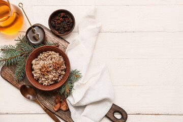 Bowl of traditional Ukrainian Kutya dish with Christmas tree branches and jug of uzvar on white wooden background