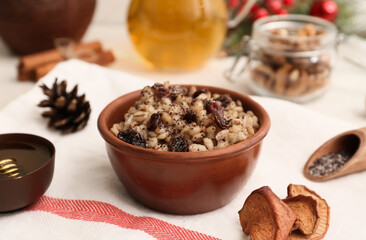 Bowl of traditional Ukrainian Kutya dish and pine cone on white background, closeup