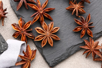 Slate board with aromatic star anise spice on grunge background, closeup