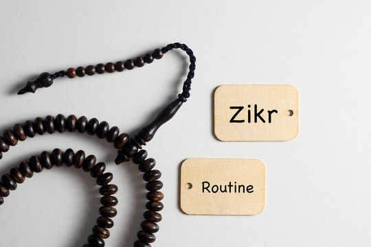 Prayer beads with two wooden plaques engraved "Zikr" and "Routine" on a white background, representing spiritual discipline, mindfulness, and daily devotional practice.