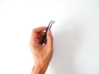 Black tweezers are being held against a white background