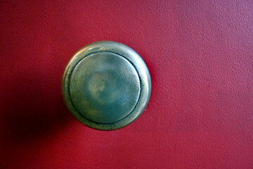 MANILLA VINTAGE DE METAL BRONCE ANTIGUO SOBRE PUERTA ROJA 