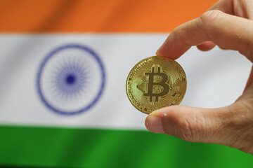 Bitcoin BTC on stack of cryptocurrencies with India flag in background. The cryptocurrency coin is golden and in focus.