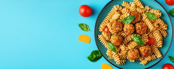 A vibrant plate of fusilli pasta with meatballs, garnished with fresh basil and surrounded by cherry tomatoes on a bright blue background.