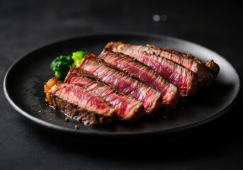 Medium rare sliced beef steak on black plate