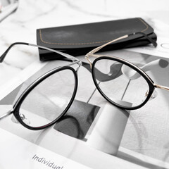 A glasses on a marble table, with some decorations on the side, there is a glasses case next to it, close up glasses details.