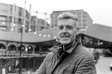 Smiling senior man posing in urban setting, grainy analog effect