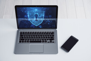 Laptop with a shield lock icon on the screen placed on a white desk next to a smartphone. Symbol of cybersecurity and data protection. 3D Rendering