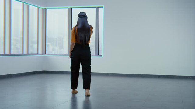 Creative Asian female designer wearing VR headset uses online design software to create interior in office room or apartment in 3D virtual space. Augmented reality technology. Futuristic VFX animation
