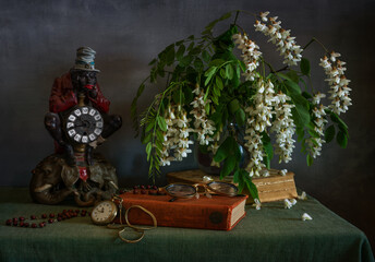 A bouquet of fragrant white acacia with a figurine of a watch, a pocket watch on a chain, glasses...