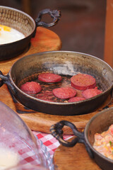  salami sausage in pan served with cheese on table 