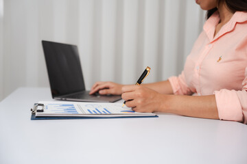 A close-up of a businesswoman working on a laptop in an office. As an accountant, she records financial data, verifies documents, manages income and expenses, ensuring accurate financial reporting