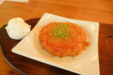 kunafa with a wipe cream on a plate .