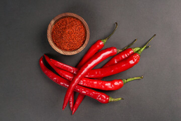 Large red chili and chilli powder served on wooden bowk isolated on a black background