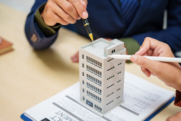 Asian business professionals and lawyer meet at desk, discussing city planning and high-rise...