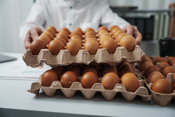 A businessman checks eggs at a work table in a factory, ensuring cleanliness and freshness. Food...
