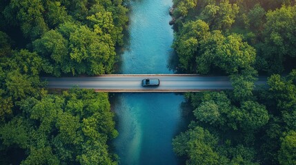 Aerial View of a Car Driving Across a Bridge Over a River in a Lush Forest