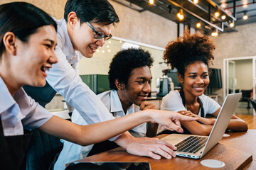 Coffee shop owner and young business team collaborate in project brainstorm meeting using a laptop. Startup teamwork concept colleagues discussing planning for success.