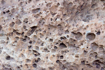 Brown basalt stone texture, porous volcanic rock throughout the stone, rough texture, brown basalt stone background, abstract background.