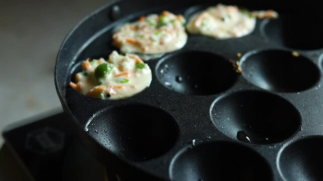 Appam or Mixed dal or Rava Appe South Indian dish preparation on iron pan
