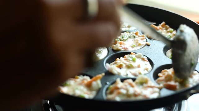 Appam or Mixed dal or Rava Appe South Indian dish preparation on iron pan