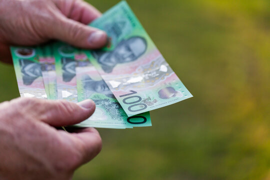 Middle aged man&rsquo;s hand holding hundreds of dollars of Australian cash