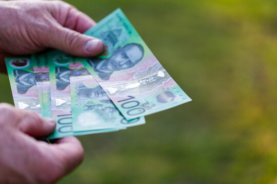 Middle aged man&rsquo;s hand holding hundreds of dollars of Australian cash