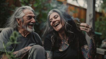 Joyful senior couple with tattoos sharing a marijuana joint.