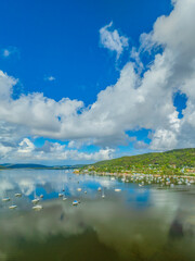 Naklejka premium Aerial views over the bay with clouds, reflections and boats
