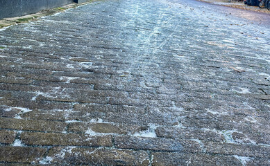 almost invisible black ice is covering a sidewalk