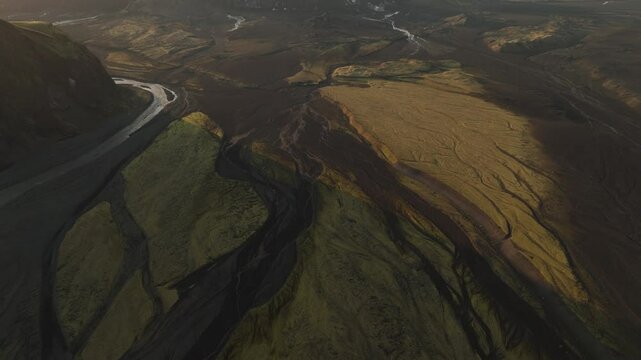 Aerial view of an expansive valley in Thakgil, Iceland, with glacial rivers winding through rugged terrain under a golden sunset.