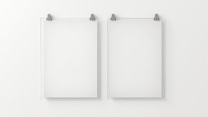Nails for picture hanging. Two empty frames with metal hooks hang on a white wall. Each frame features four black corner pins securing the transparent cover.