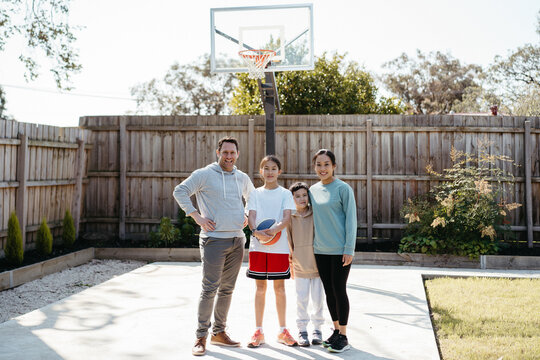Happy family standing on concrete ground in the yard of their home