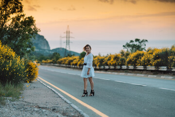 Obraz premium A woman is walking down a road with yellow flowers in the background