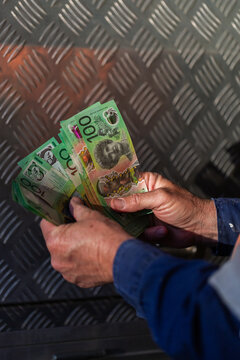 Middle aged man holding hundreds of dollars of Australian cash beside meal tool box on ute