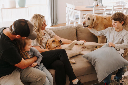 Happy family with two kids and dogs together on lounge in loungeroom at home