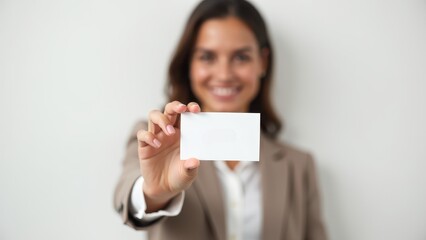 Realtor business card. A smiling woman in a suit holds a blank business card towards the camera, with focus on the card and a blurry background.