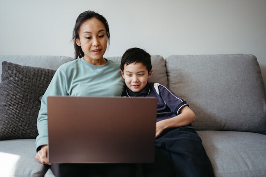 Mum working on her laptop with her son on the couch