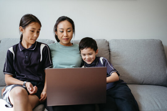 Mum working on her laptop on the couch with her kids.