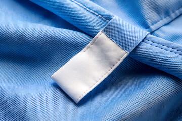 White blank laundry care clothes label on blue shirt fabric background