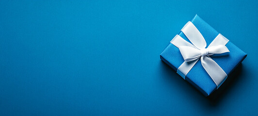 Bright blue gift wrapped in white ribbon placed on a simple blue background ideal for celebrations and holidays