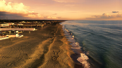 Aerial view over sea at Rome coastline with winter sky and bright sunset with closed beach facilities illuminated of natural sun lights