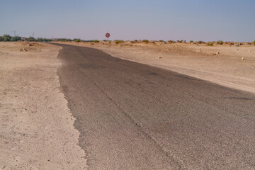 an asphalt road leading through a flat section of desert