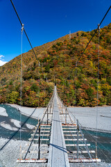 紅葉に染まる山々の中にたたずむ吊り橋